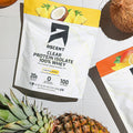 Ascent Clear Protein Isolate 100% Whey package on a table with a coconut and pineapple.