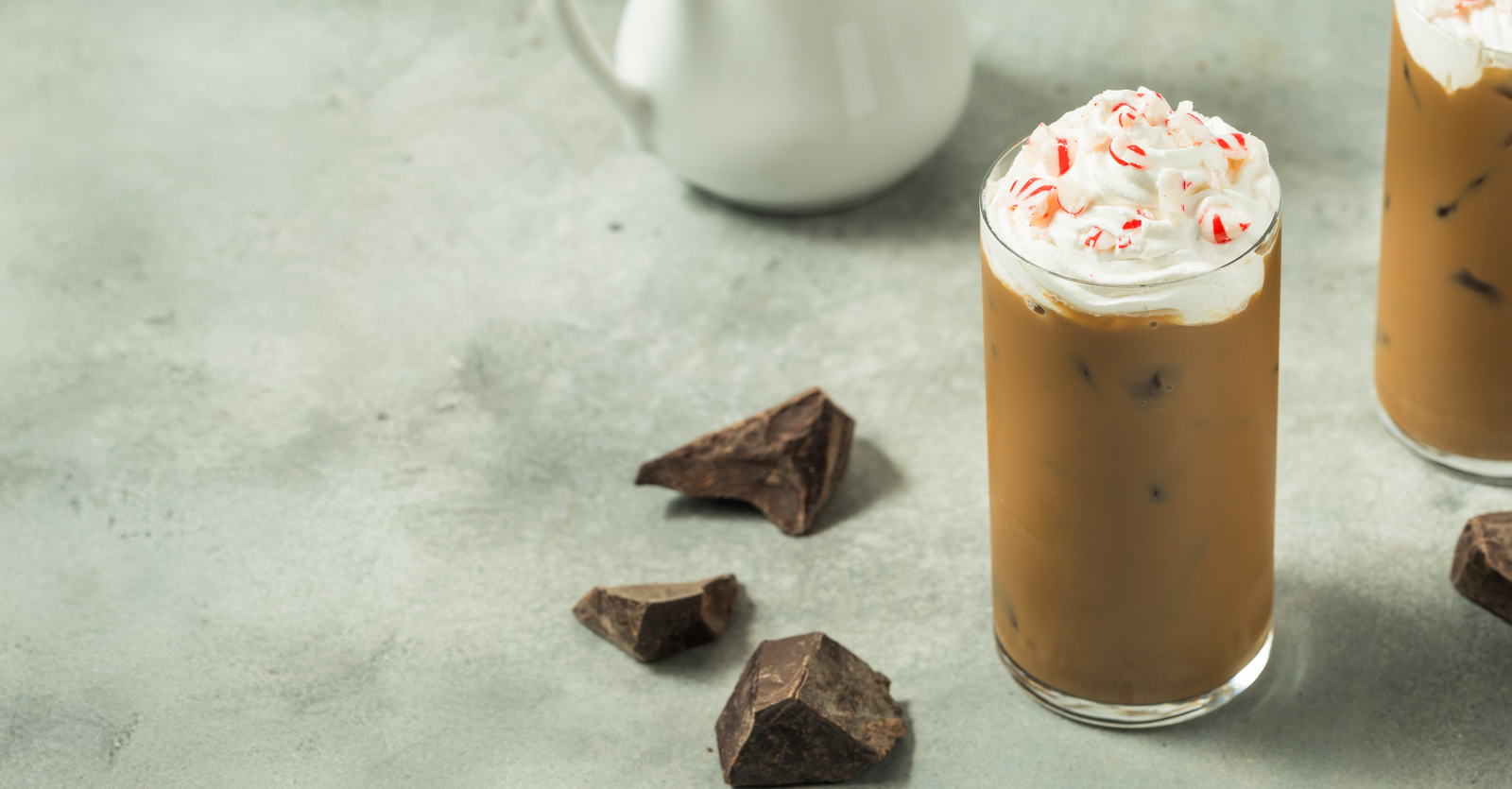 Peppermint mocha in a glass with a candy cane and chocolate pieces