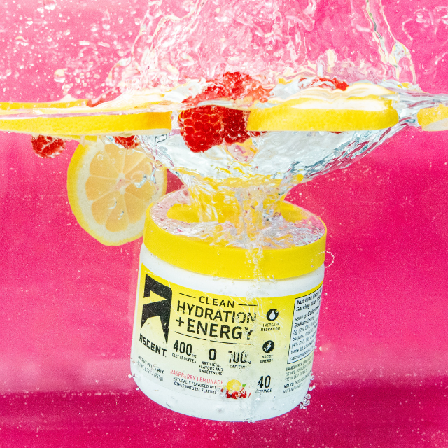 Jar of Clean Hydration + Energy powder submerged in water with lemon slices and raspberries
