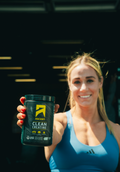 Woman holding a container of 'Ascent Clean Creatine' powder in a gym setting.