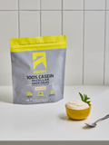 Package of Ascent 100% Casein Micellar Casein Isolate on a white surface with a bowl of protein shake.