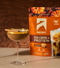 a bag of pumpkin spice iced coffee + protein next to an espresso martini made with pumpkin spice iced coffee + protein in an espresso glass.