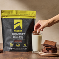 Ascent Brownie Batter 100% Whey protein blend package with a hand dipping a brownie into milk.