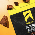 Brownie pieces on top of a bag of Ascent Brownie Batter Whey Protein