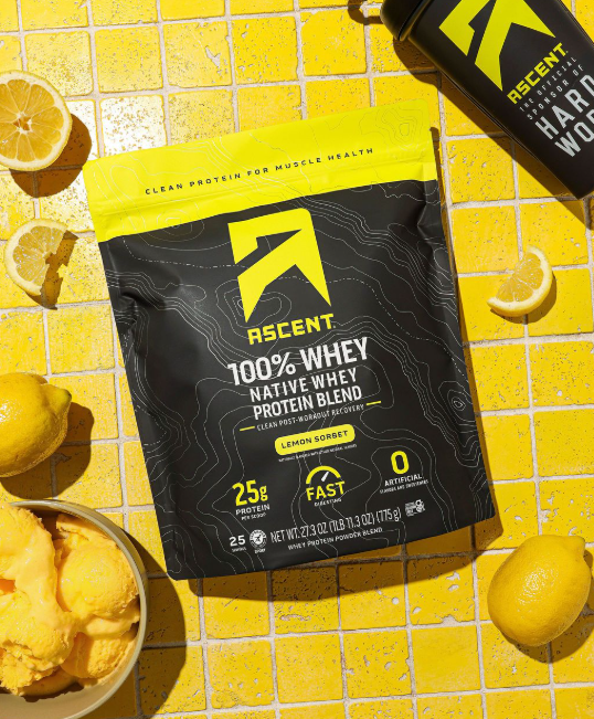 Ascent protein package with lemon slices on a yellow tiled background