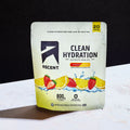 A stand-up pouch of ASCENT Clean Hydration Electrolyte Drink Mix, strawberry lemonade flavor, standing on a white marble-like surface against a black background.