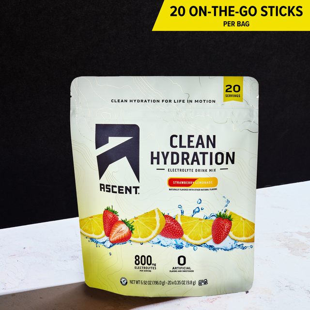 A stand-up pouch of Ascent Clean Hydration electrolyte drink mix in strawberry lemonade flavor, shown on a white surface against a black background. A yellow banner at the top reads '20 ON-THE-GO STICKS PER BAG'.