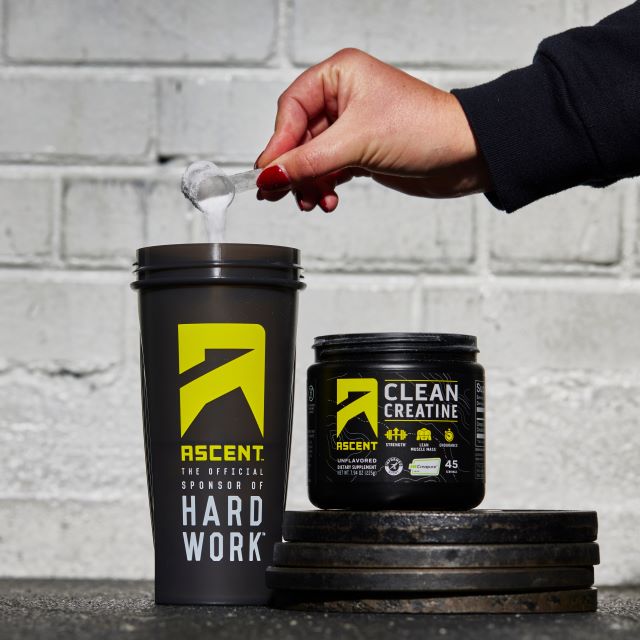 This is an image of someone pouring a 5 gram creatine scoop into a protein shaker