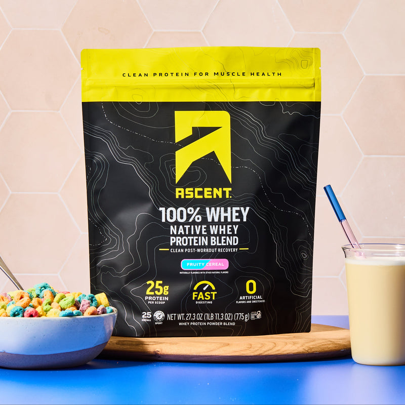 Ascent Fruity Cereal Whey Protein Blend package on a table with cereal and a glass of milk.