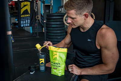 ascent protein athlete pouring a scoop of protein powder into a blender bottle