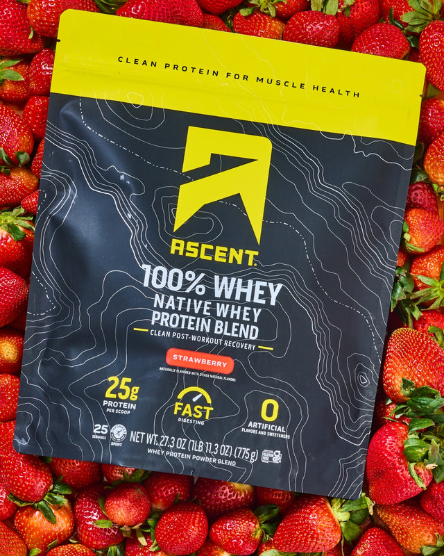 black & yellow bag of Ascent protein powder on a bed of strawberries