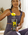 Female dressed in athletic wear indoors pouring a scoop of Ascent powder into a Ascent-branded cup.